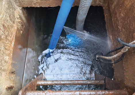 Fuite d'eau dans un puits souterrain avec jets d'eau autour d'une conduite endommagée